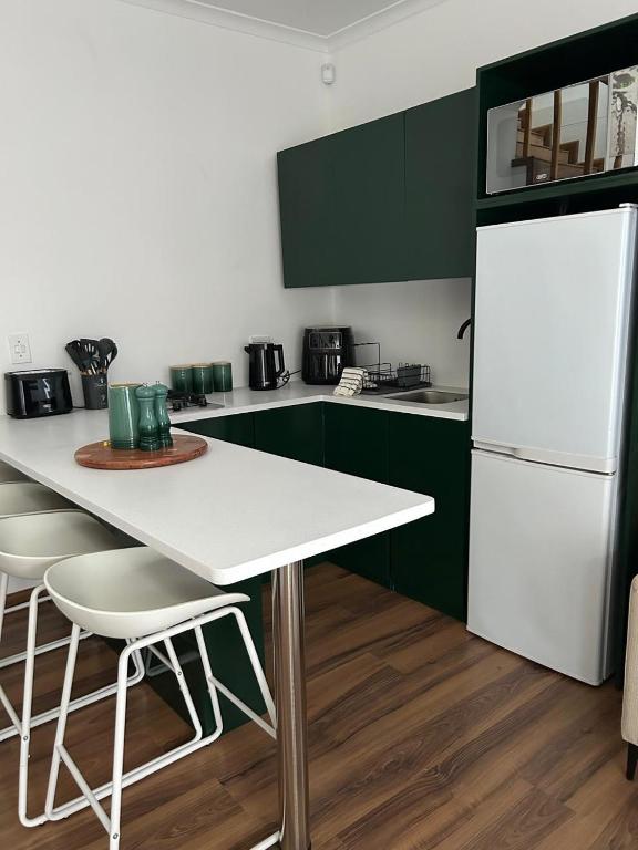 a kitchen with green cabinets and a white refrigerator at Serenity Green House near Constantia Winelands in Square Hill