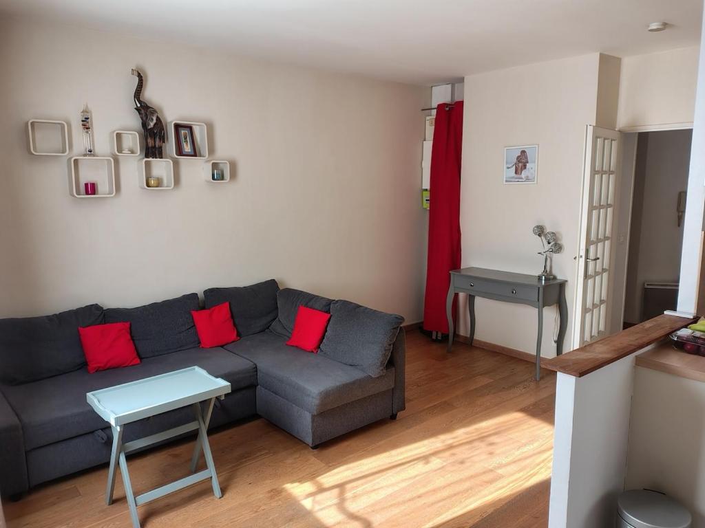 a living room with a gray couch and red pillows at Prieuré Maisons-Laffitte in Maisons-Laffitte