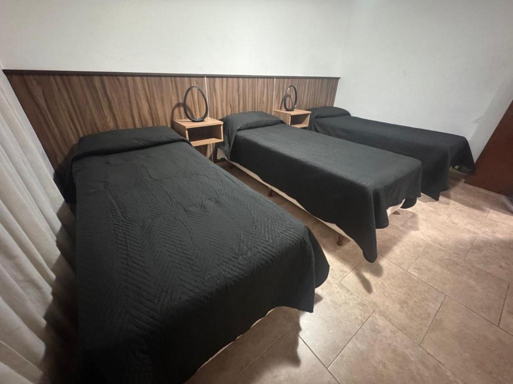 una habitación con tres camas en una habitación en Hotel Santa Bárbara, en La Falda