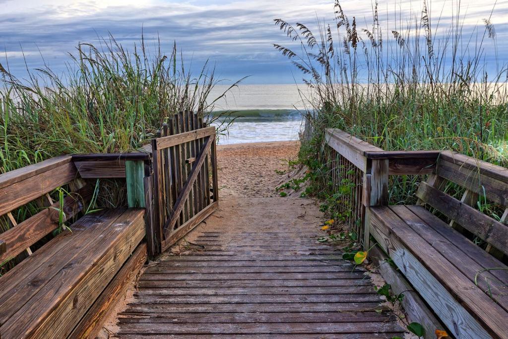 Coastal Breeze Luxurious Coastal Villa Steps to Cinnamon Beach Beautiful Pools! Perfect for Families في Hawthorne: درج خشبي يؤدي إلى شاطئ مع المحيط