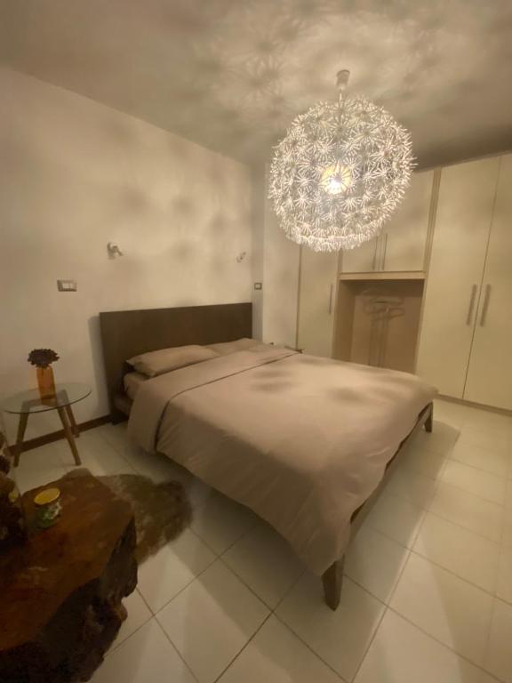 een slaapkamer met een groot bed en een kroonluchter bij Appartamento Catalina in Saint-Pierre