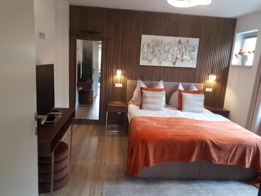 a bedroom with a large bed with an orange blanket at Schafberg Luxury Apartment in St. Wolfgang