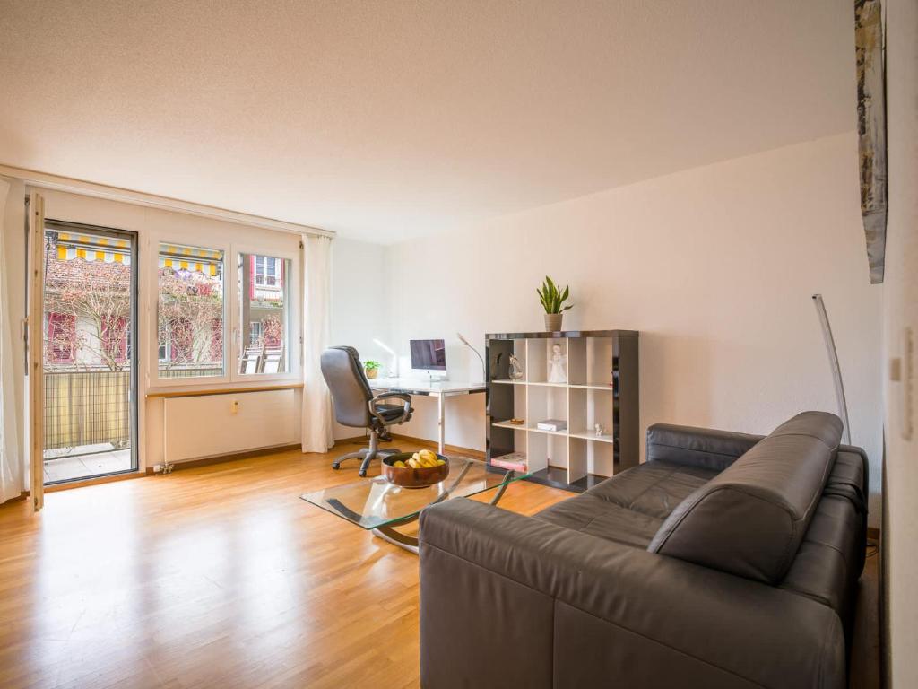 a living room with a couch and a desk at Central Bern Flat - Balcony & Bundeshaus View in Bern