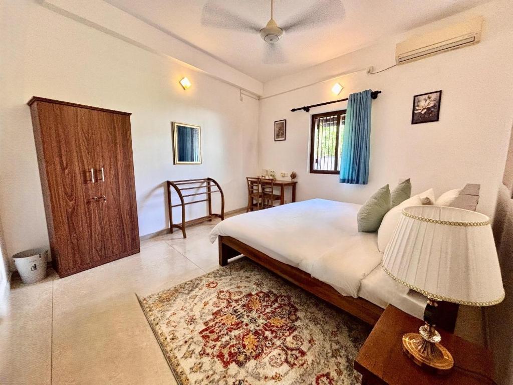 Nest Villas في سري جايواردنيبورا كوته: غرفة نوم بسرير ومصباح وطاولة