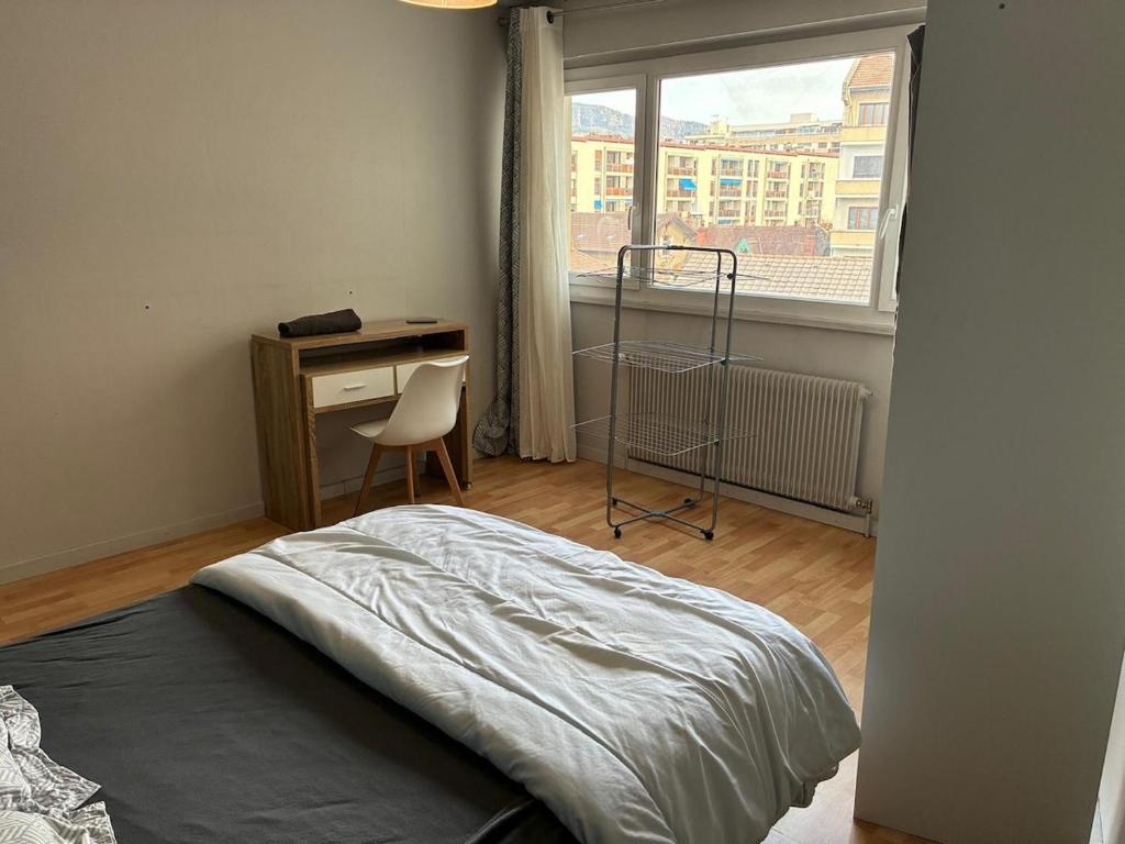Un dormitorio con una cama y un escritorio y una ventana. en Green room - Wifi - Centre ville - Cosy, en Annemasse