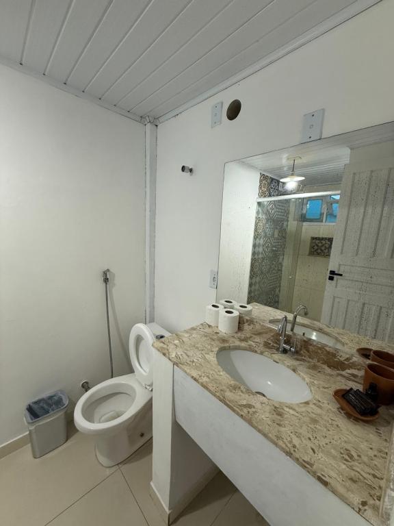 a bathroom with a toilet and a sink and a mirror at Pousada Quintal da Praça in Prado
