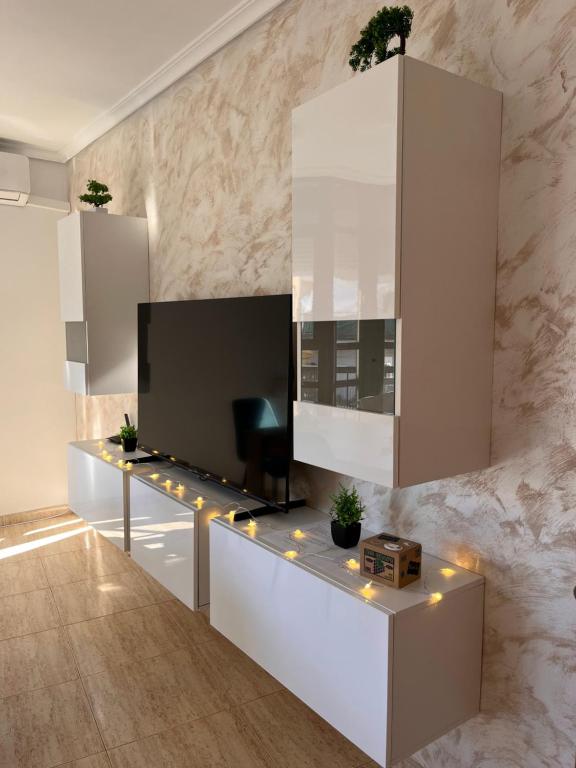 Casa Blanca - apartamento en Gandia في غانديا: غرفة معيشة مع تلفزيون بشاشة مسطحة على الحائط