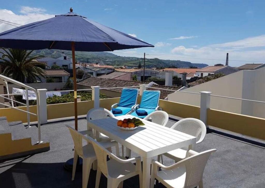 a white table and chairs with an umbrella on a roof at Gloria's House in Lagoa