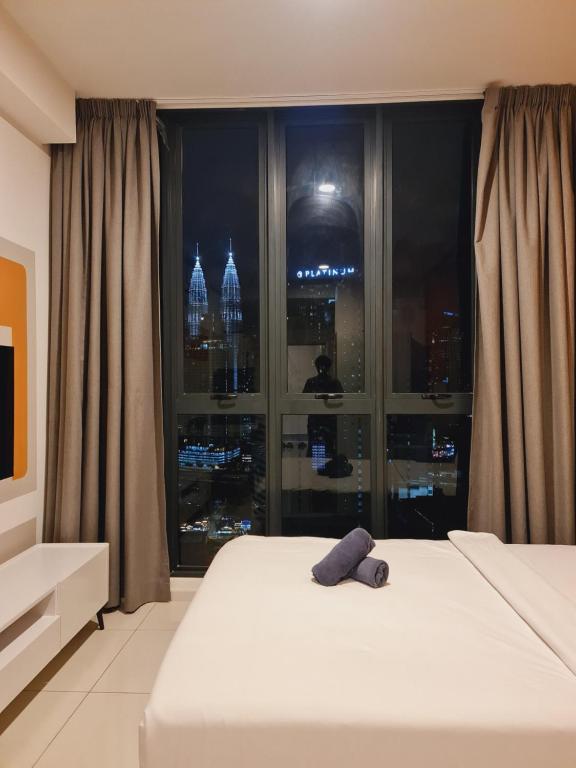 a bed with a stuffed animal on it in front of a window at KLCC View City Center At Majestic residence in Kuala Lumpur