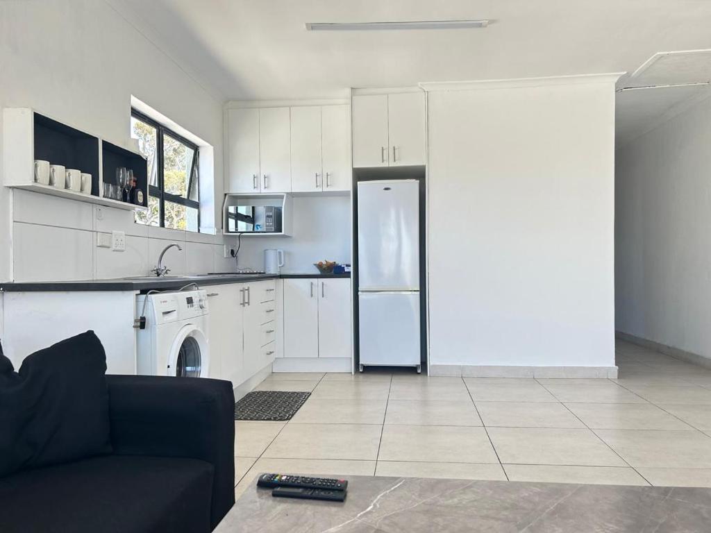 une cuisine avec des armoires blanches et un réfrigérateur dans l'établissement Shine house, à Somerset West