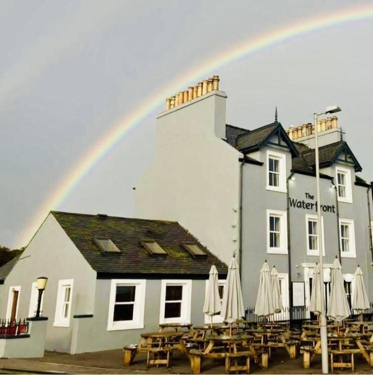 Ein Regenbogen über einem Restaurant mit Tischen und Sonnenschirmen in der Unterkunft The Waterfront in Portpatrick