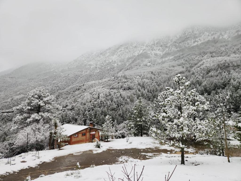 a house on a snow covered hill with a mountain at Cabañas La Moneda in Rancho La Carolina