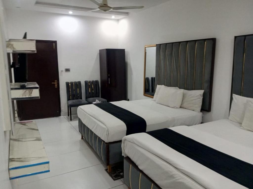 a hotel room with two beds and a mirror at Hotel The Tulip in Lahore