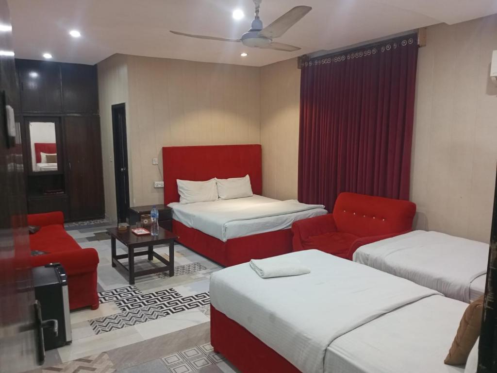una camera d'albergo con due letti e una sedia rossa di Hotel The Tulip a Lahore