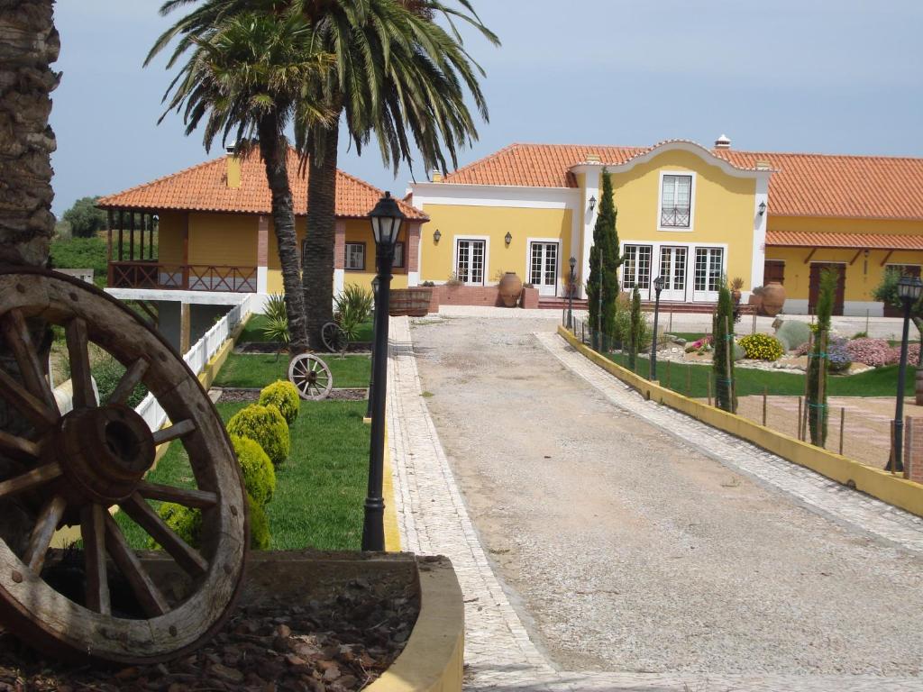 una gran casa amarilla con una rueda delante de ella en Casa Agricola Quinta Da Junqueira, en Reguengo Grande