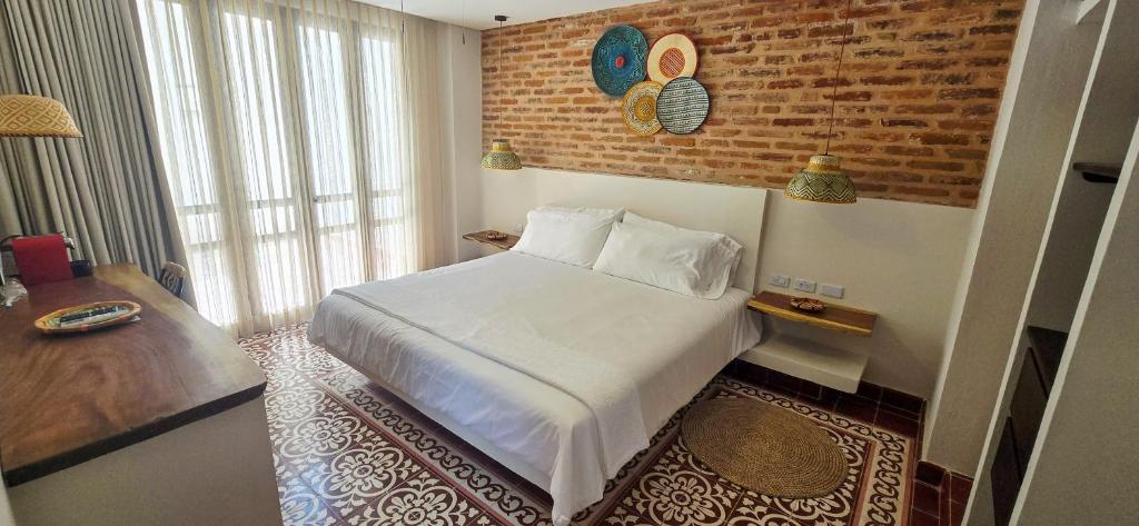a hotel room with a bed and a brick wall at Hotel Casa de la Acequia in Santa Marta