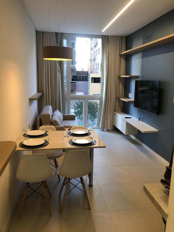 a living room with a table and chairs and a television at Baltico302 in Capão da Canoa