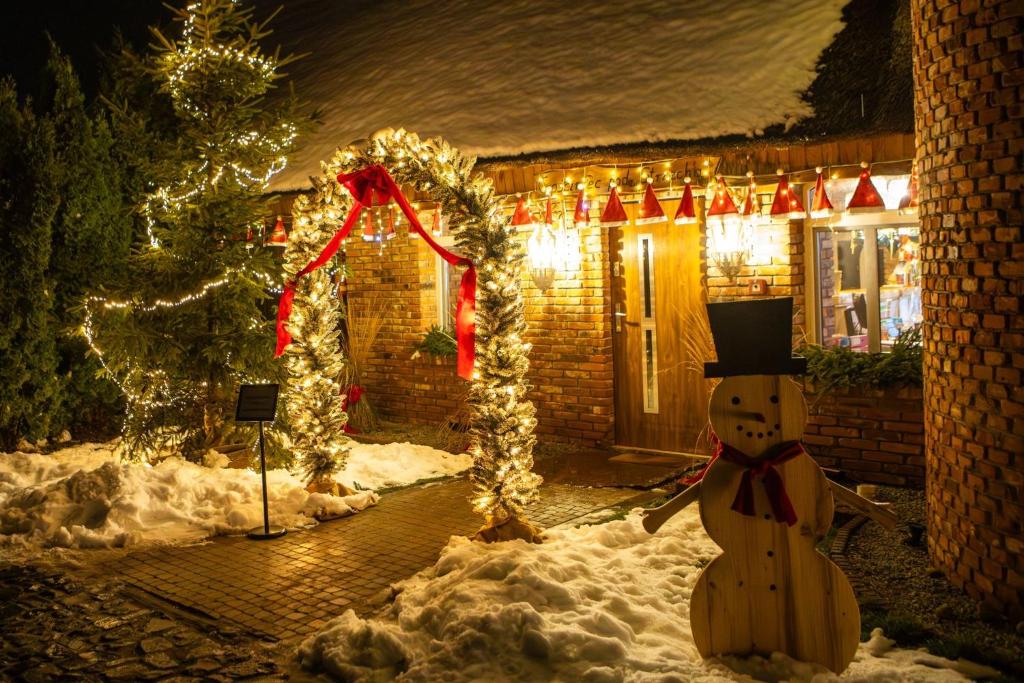 Skansen Bicz Resort في Stare Miasto: منزل مزين بأضواء عيد الميلاد ورجل ثلج