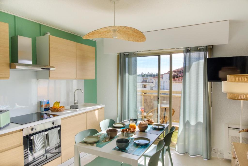 a kitchen with a table and chairs in a kitchen at Maïmo Cosy Appartement rénové Centre Ville 300m plage, Clim, Parking in Sainte-Maxime