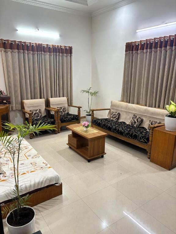 a living room with couches and tables and curtains at Tranquil Trails-Sharvari Villa-Nashik in Nashik