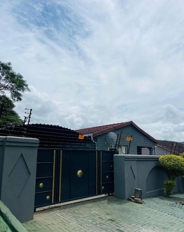 a house with a blue gate and a building at Mbombela Stay in Nelspruit