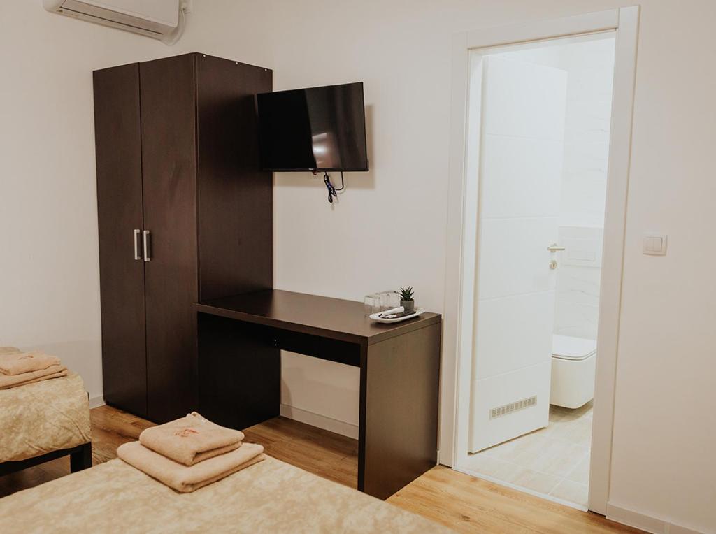 a bedroom with a desk and a tv on a wall at Gallus Inn in Aleksinac