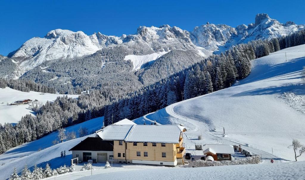 een gebouw in de sneeuw met bergen op de achtergrond bij Ferienwohnung Unterdürmoos in Annaberg im Lammertal