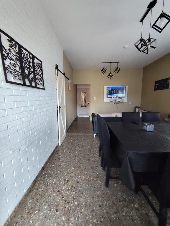 Un comedor con mesas negras y una pared blanca. en Casa vacacional 6 personas, en Santa Teresita