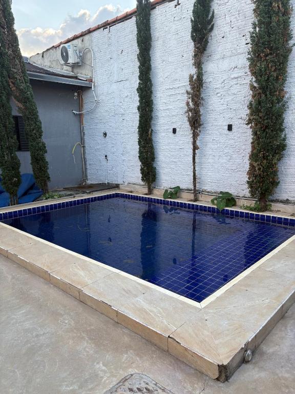 a swimming pool in front of a building with trees at Espaço Atlântico in Goiânia