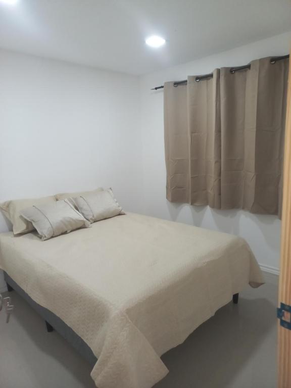 een bed in een witte kamer met een raam bij ChicPDD in Punta Del Diablo