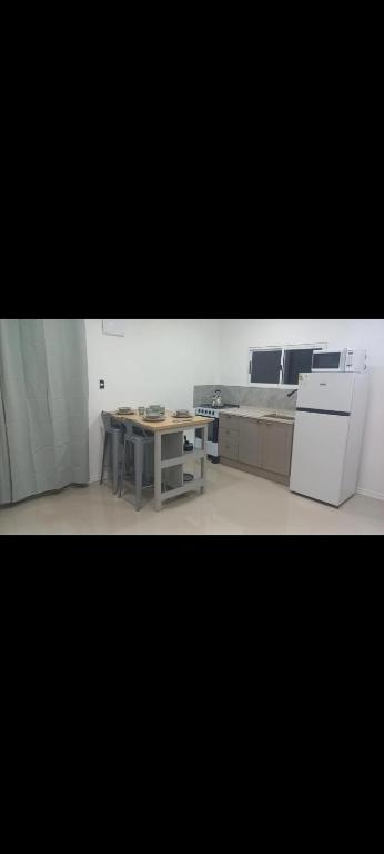 a kitchen with a table and a white refrigerator at ChicPDD in Punta Del Diablo