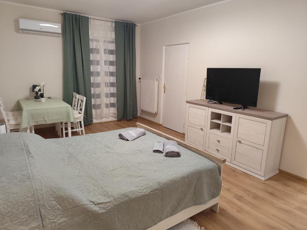 a bedroom with a bed and a flat screen tv at Tímea Apartman Pécs in Pécs