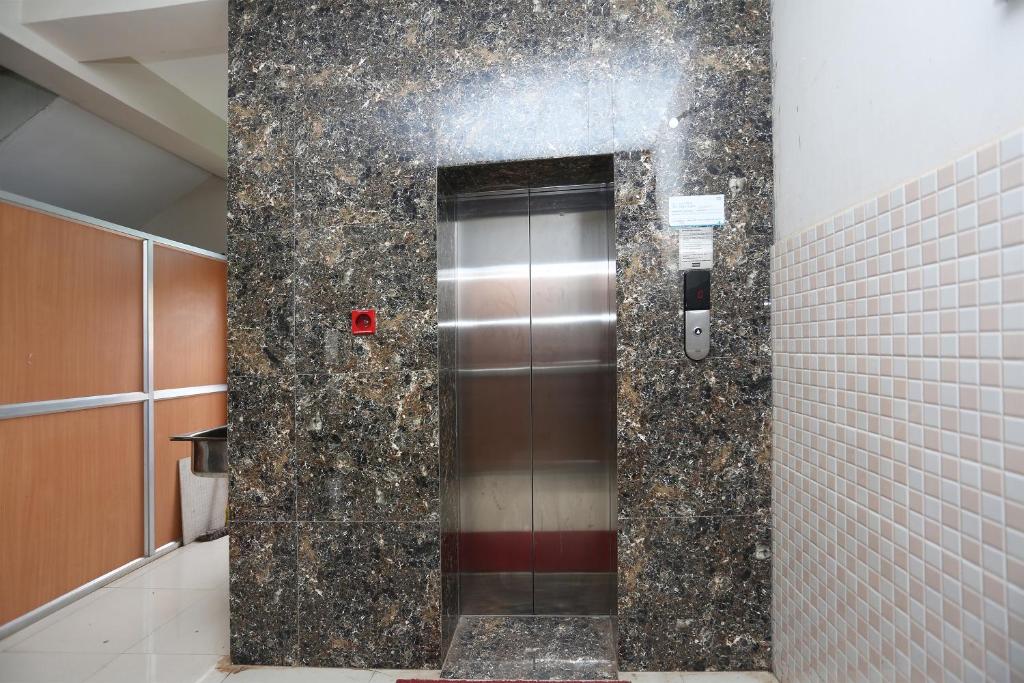 a metal elevator in a bathroom with a tile wall at Collection O KIIT Square Bhubaneswar Formerly Nilay Classic in Bārang