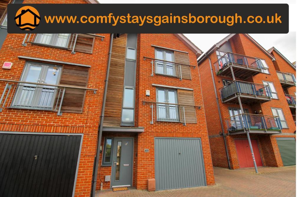 an orange brick building with grey doors and balcony at Luxury Riverside Living in Morton