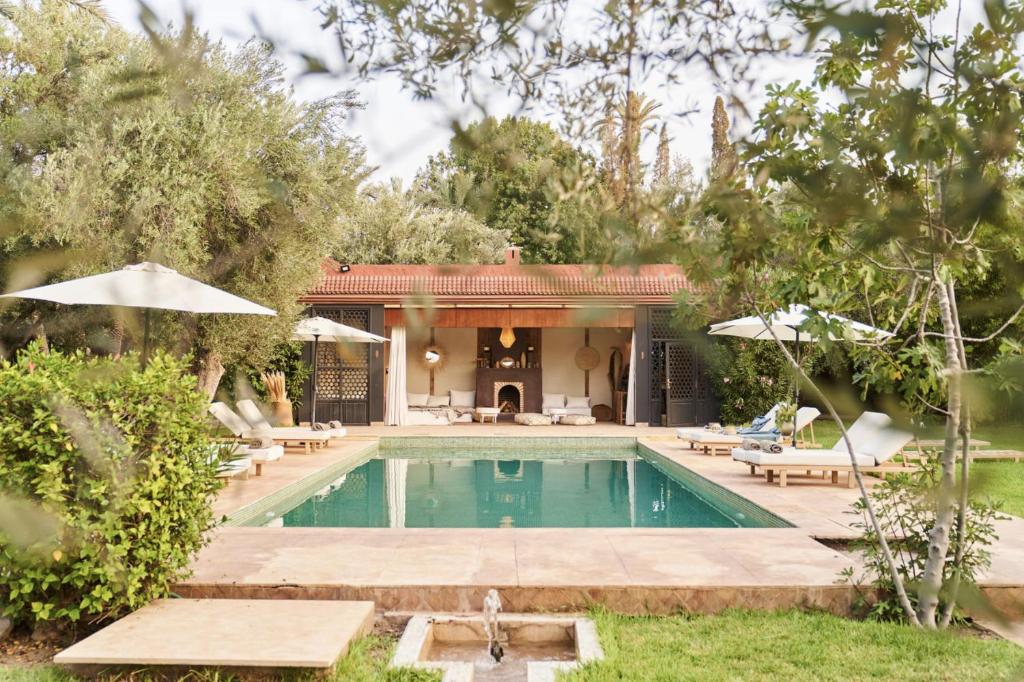 a swimming pool with umbrellas and a house at Bab Akoul Palmeraie - Boutique Hotel & Spa in Marrakesh