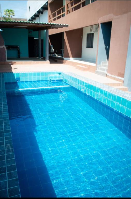 ein blauer Swimmingpool vor einem Gebäude in der Unterkunft Flat Coqueirinho in Conde