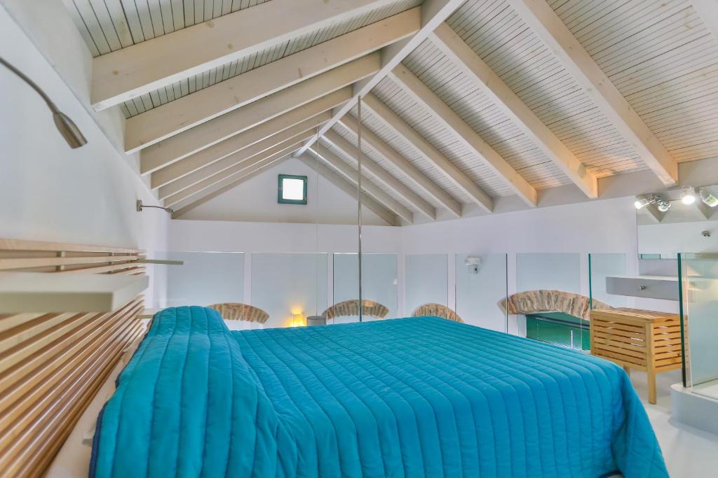 a bedroom with a blue bed in a room with wooden ceilings at Annika Deluxe Apartments in Symi