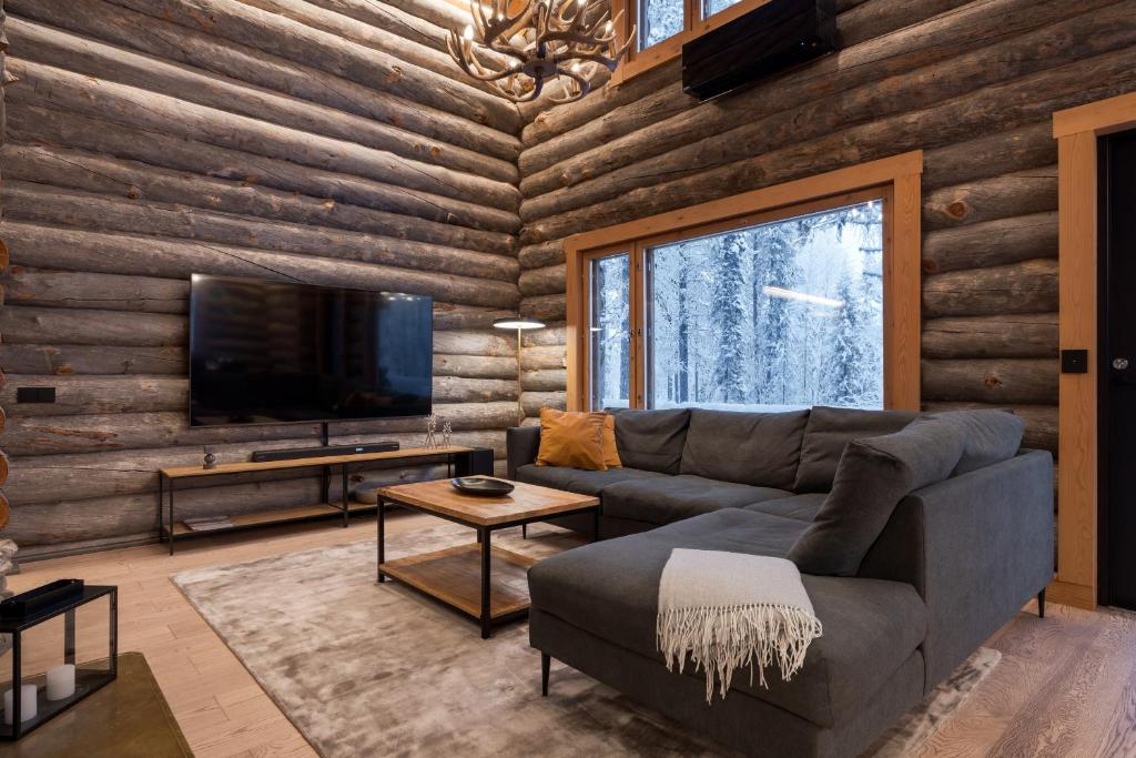 a living room with a couch and a flat screen tv at Kelokurki - The Luxury Lodge Where Serenity Meets the Northern Lights in Levi