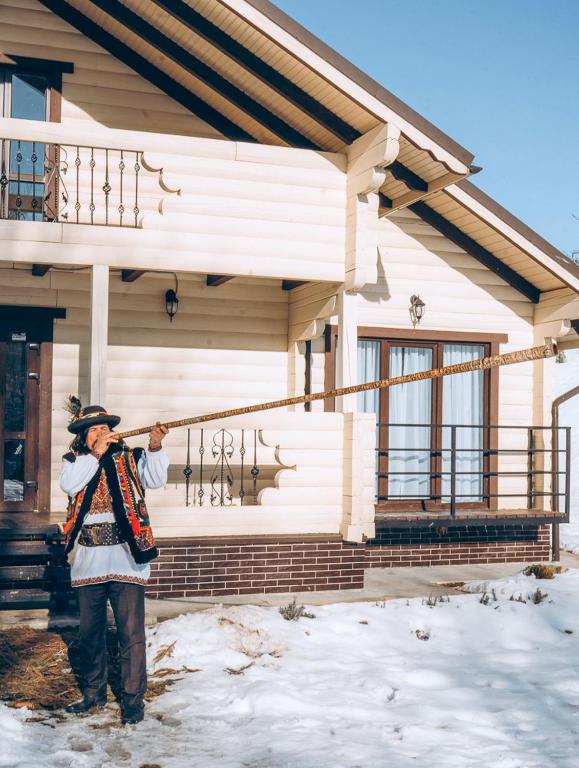 Вілла у горах في Krasnik: رجل يقف أمام منزل في الثلج