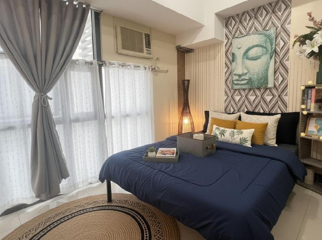 a bedroom with a blue bed and a window at BGC Mckinley Center Prime Accommodations in Manila
