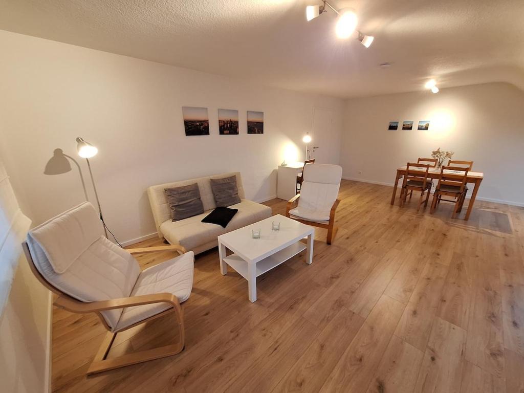 a living room with white furniture and a table at Helle, großzügige Dachgeschosswohnung in Aichtal 