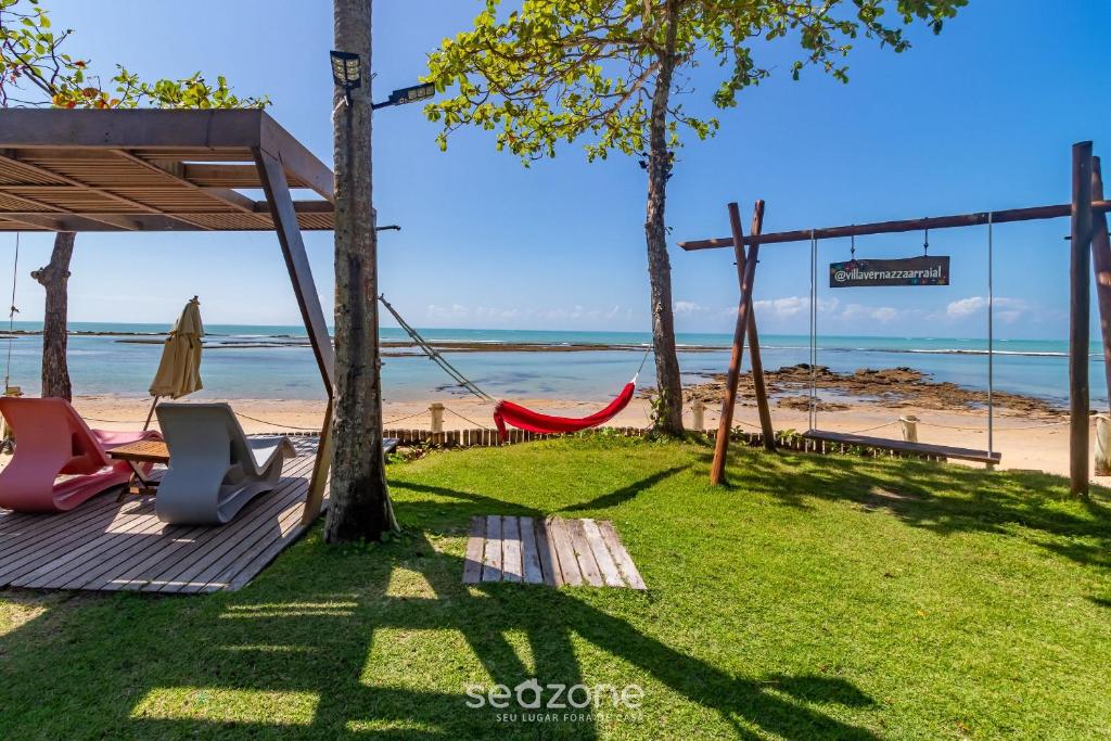 a patio with a hammock and a view of the beach at Aptos equipados em condomínio à beira-mar com área de lazer e piscina – VVAs in Arraial d'Ajuda