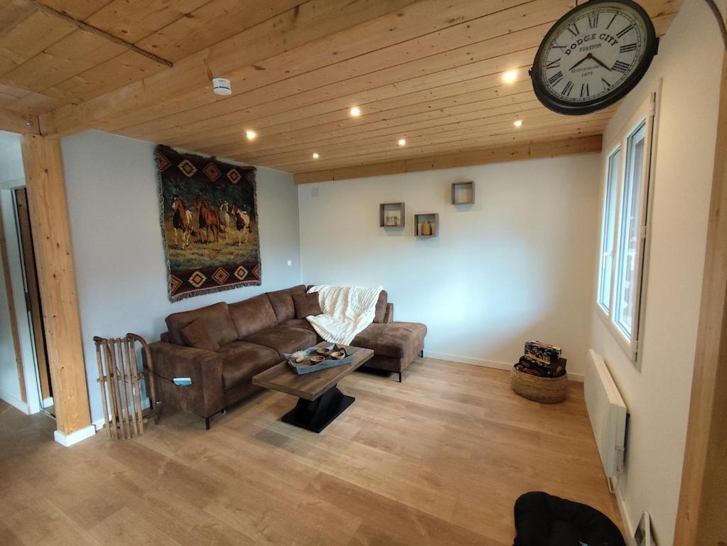 a living room with a couch and a clock on the wall at Chalet Mustang Vallée in Laruns