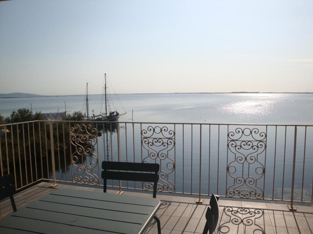 - un balcon avec un banc et un bateau dans l'eau dans l'établissement Port Rive Gauche Ostrea, à Marseillan