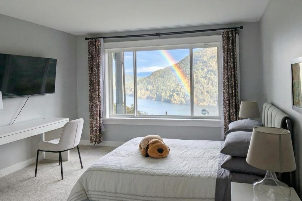 a bedroom with a large window with a teddy bear on a bed at Horizon Suite-Baylight in Malahat