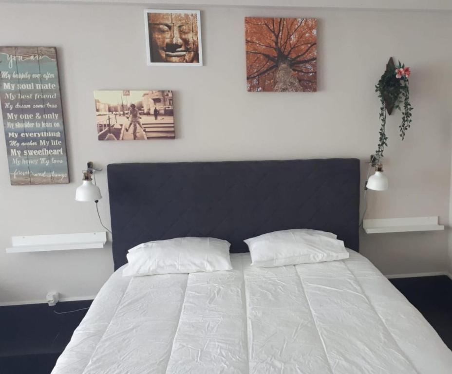 ein Schlafzimmer mit einem Bett mit zwei Kissen und Bildern an der Wand in der Unterkunft Budha GuestHouse in Porto