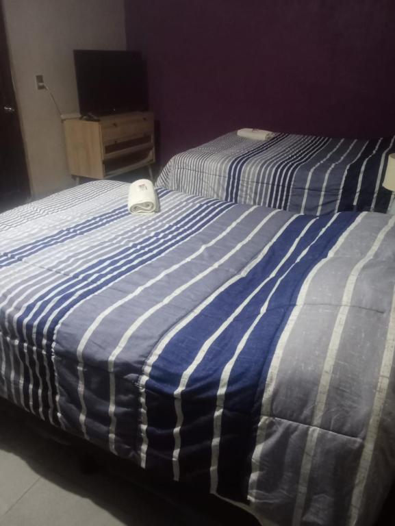 a bed with a blue and white striped blanket at casa ex hacienda casasano in Cuautla Morelos