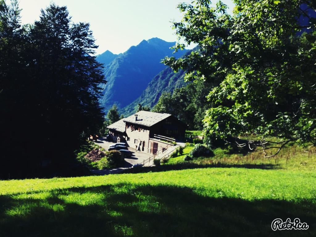 a house in a field with mountains in the background at Agriturismo Alagna in Alagna Valsesia