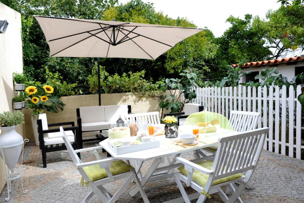 uma mesa branca e cadeiras com um guarda-sol em Casa da Ribeira em Aveiro