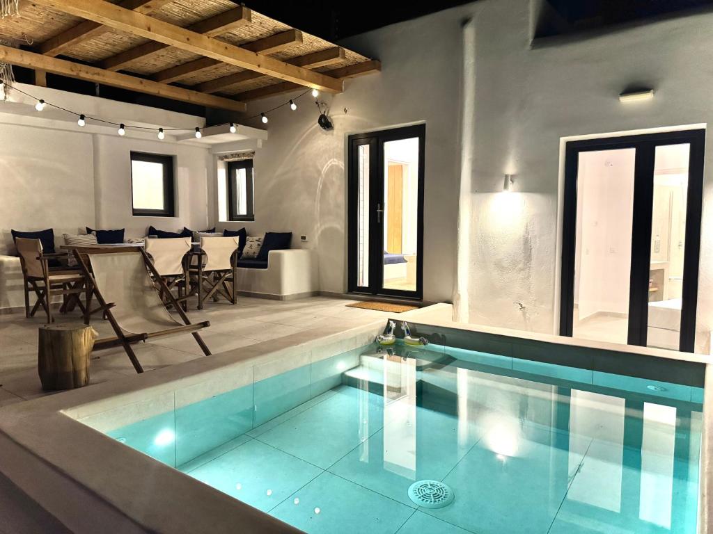 Kukulú Luxurious Cottage with Mini Private Pool في أنو ميرا: مسبح في غرفة مع طاولة وكراسي